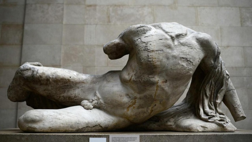 A marble sculpture of a nude male torso in a semi-reclined pose
