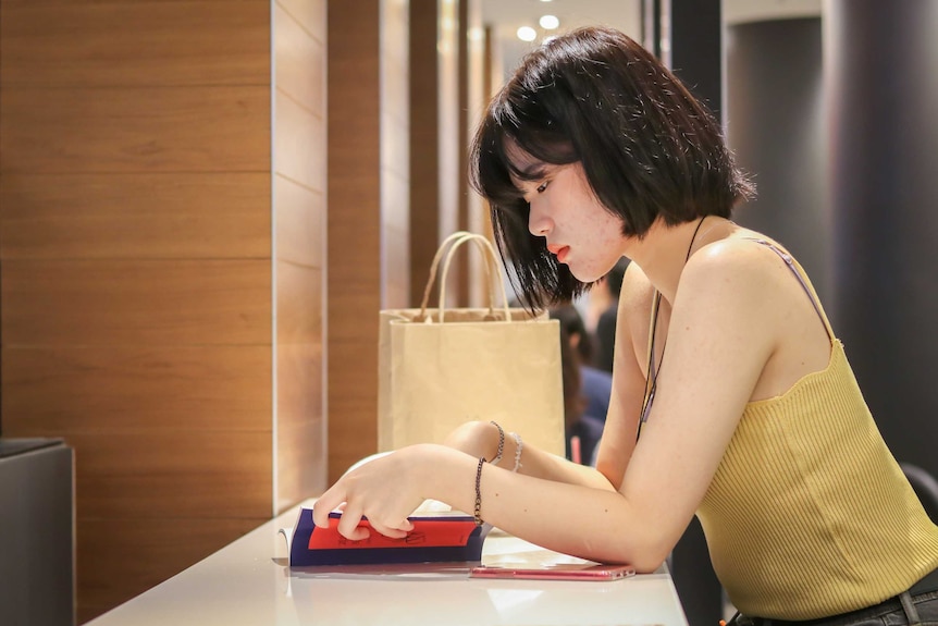 A sitting at a table and chairs reading