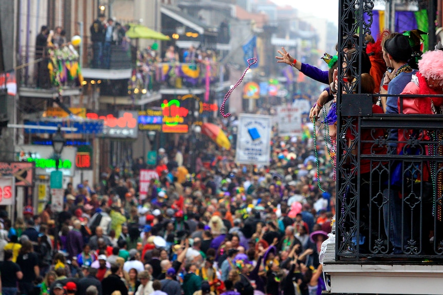 Revellers throw beads off The Royal Sonesta Hotel balcony on to Bourbon Street on Mardi Gras Day in New Orleans