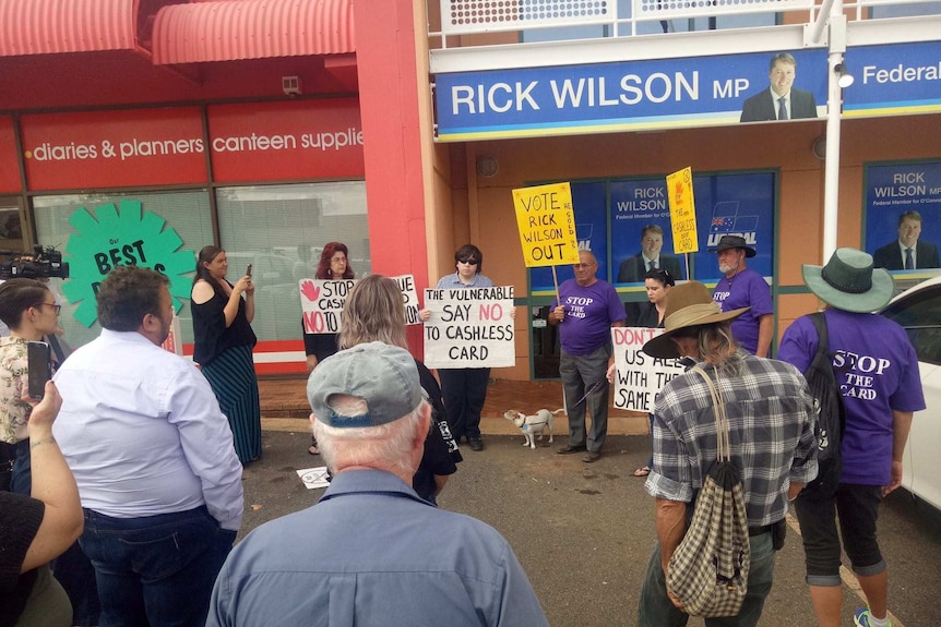 People protesting in the street holding placards about a government welfare system.