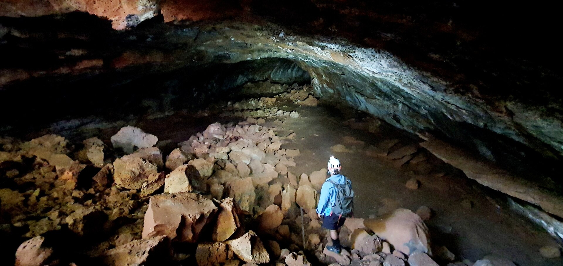 A person stands in a cave with a torch.