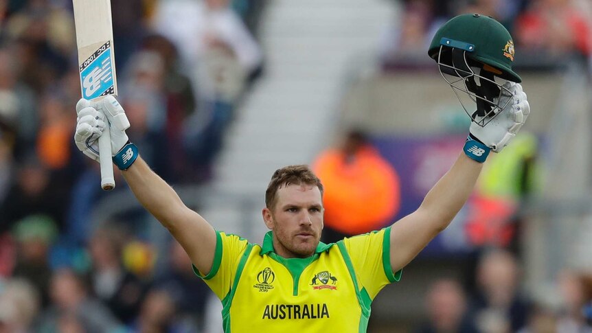 Aaron Finch puts his hands up with his bat in one hand and helmet in the other