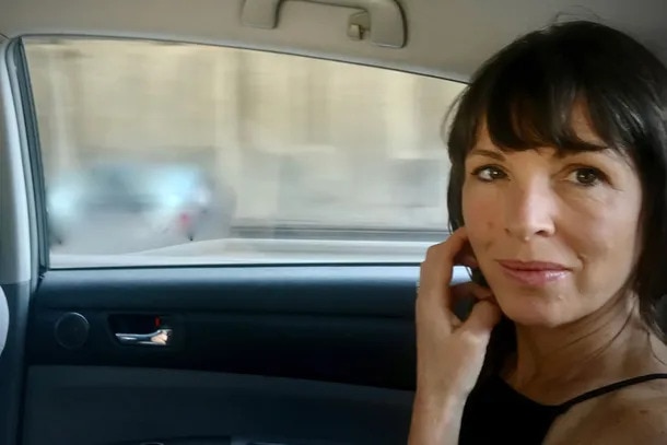 Author Rachel Cusk, who has dark hair and eyes, in the back of a car