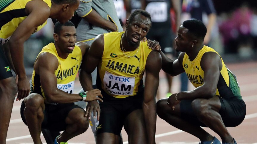 Jamaica's Usain Bolt is joined by his teammates after he pulled up injured in the final of the Men's 4x100m relay.