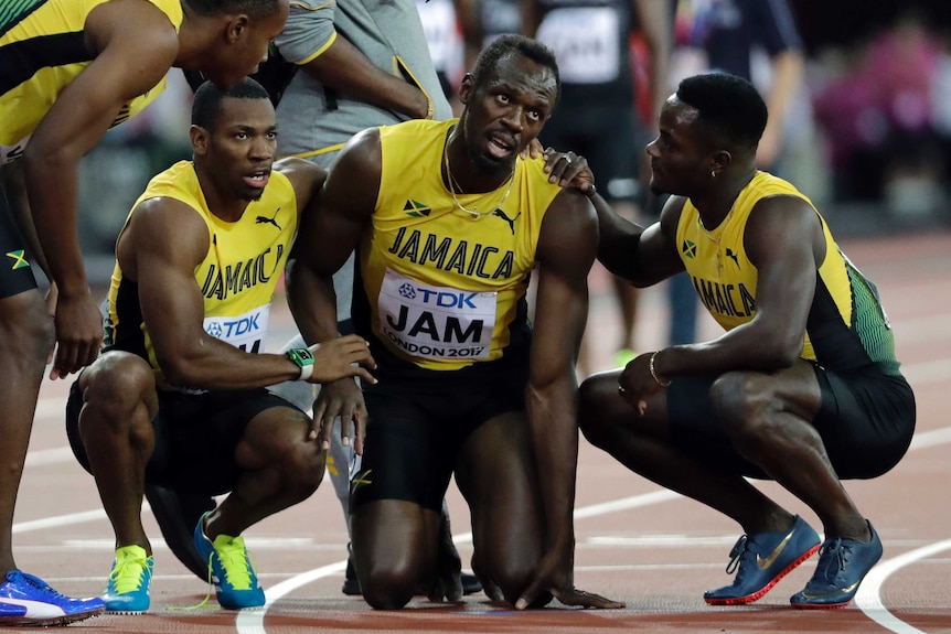Jamaica's Usain Bolt is joined by his teammates after he pulled up injured in the final of the Men's 4x100m relay.