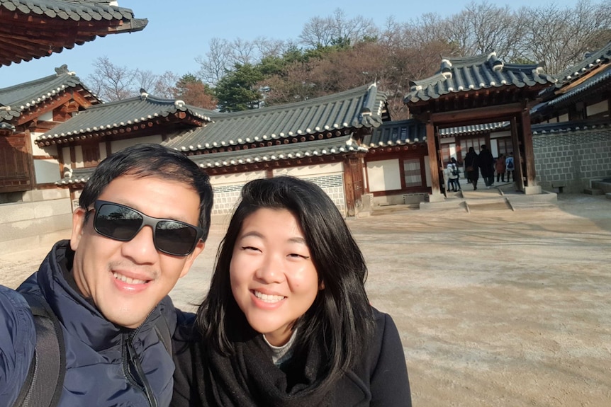 The author, Natasha Hertanto, and her father pose for a selfie in front of a tourist attraction.