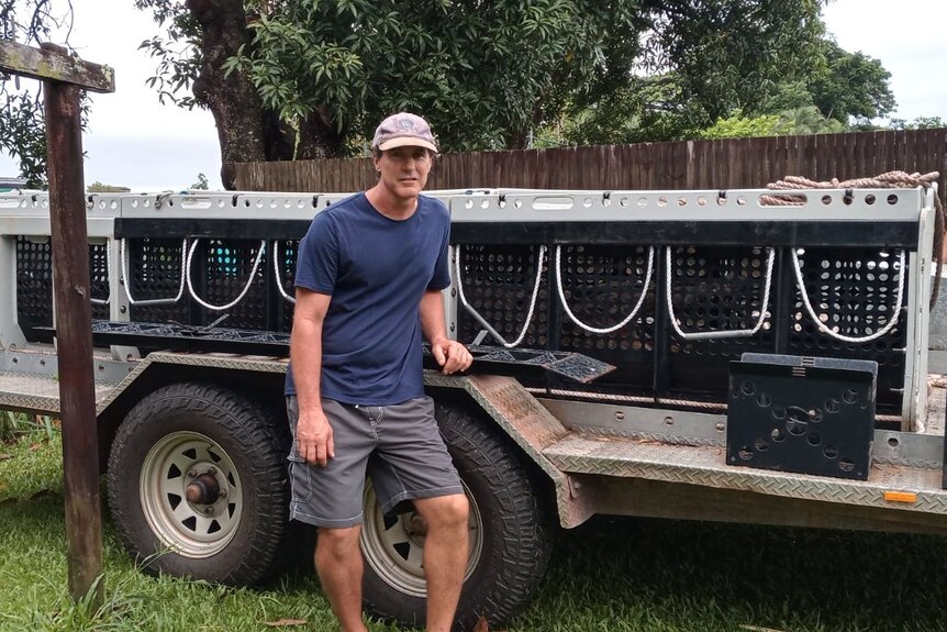 A man stands in front of a trailer loaded with a crocodile enclosure.