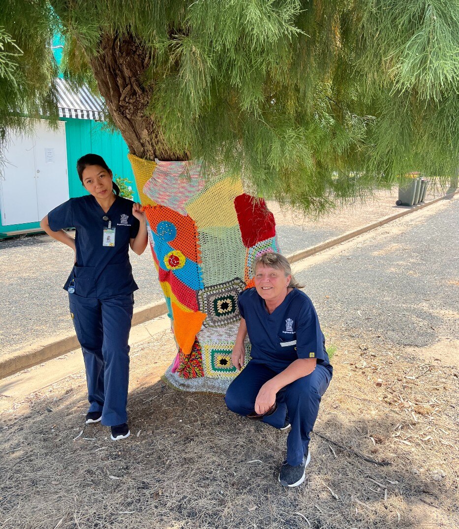 two nurses in front of a tree wrapped in wool