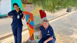 two nurses in front of a tree wrapped in wool
