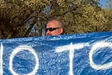 A man holds a sign outside the Woodside town hall
