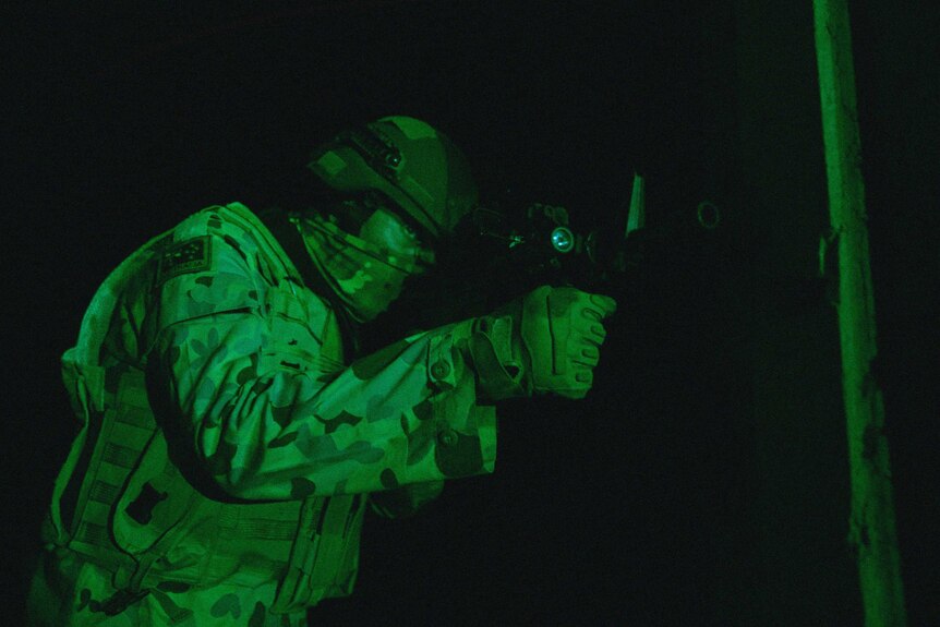 A night vision shot of a soldier looking down the sight of his weapon