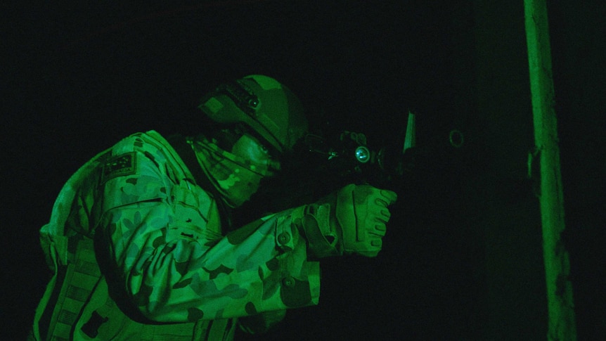 A night vision shot of a soldier looking down the sight of his weapon