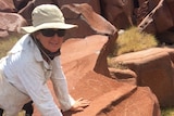 Archaeologist Jo McDonald on Enderby Island in the Dampier Archipelago with an ancient rock carving of a fish.