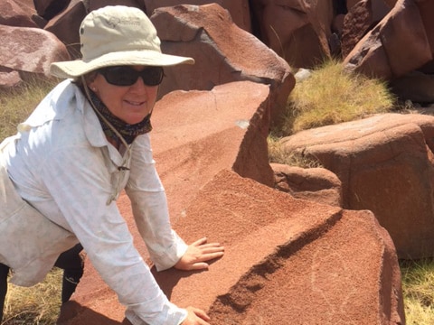 Archaeologist Jo McDonald on Enderby Island in the Dampier Archipelago with an ancient rock carving of a fish.
