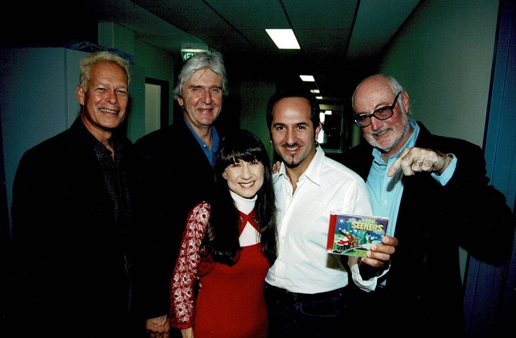 a group of four men wearing suits and a woman wearing a red dress.