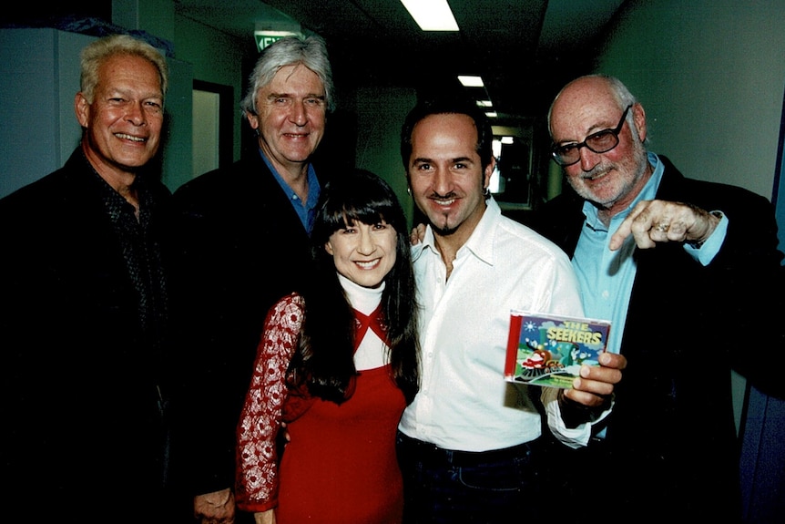 a group of four men wearing suits and a woman wearing a red dress.