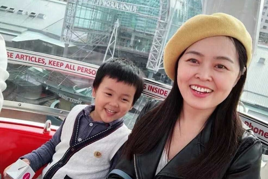 A young Chinese boy and his mother smiling at the camera.