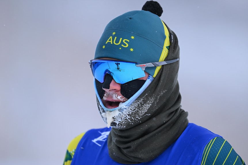 An Australian male cross-country skier with ice forming on the chin of his uniform.