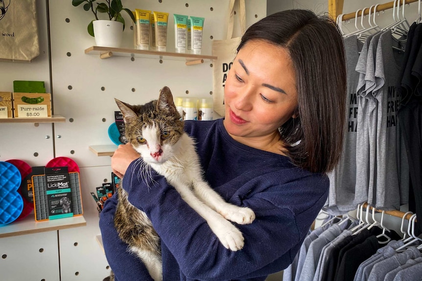 A young woman cradles a brown and white cat