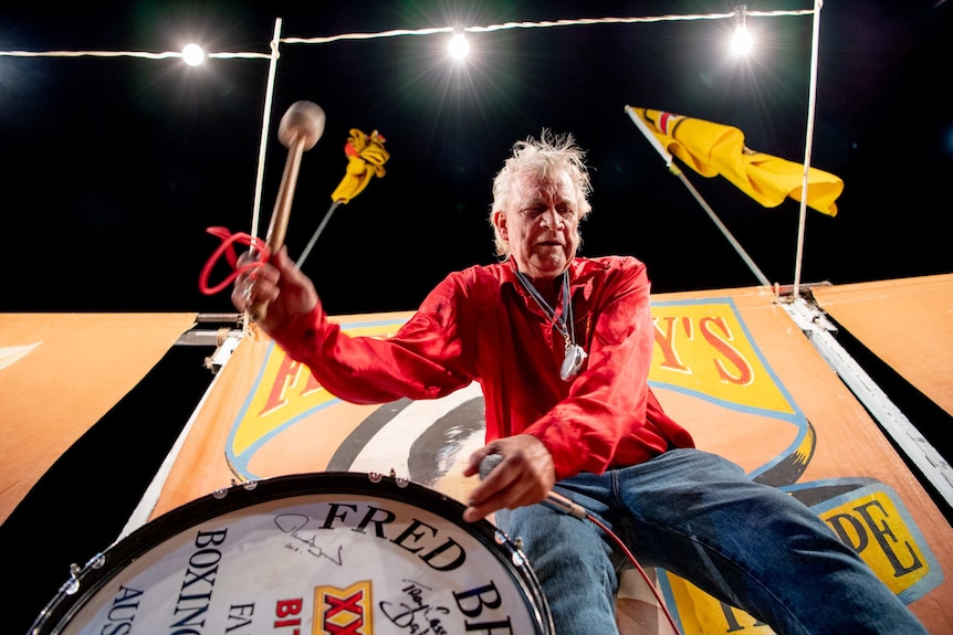 An official bangs a drum, inside the Fred Brophy boxing tent in Mt Isa.