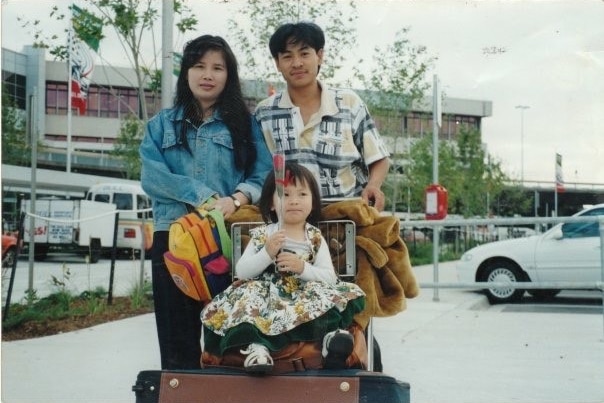 An old photo of a man, woman and young child with suitcases leaving the airport.