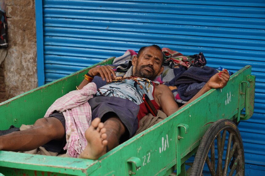 An Indian man lies in a trolley, taking a nap 