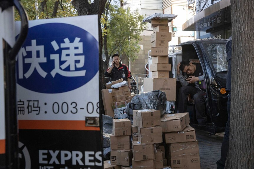 Delivery men wait to distribute parcels on the streets of Beijing.