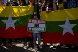 Protesters hold flags and a small girl holds a placard reading 'no more killing in Myanmar'