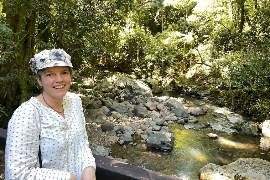 Women standing next to creek in forest.