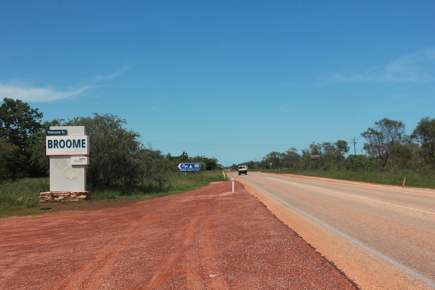 A road with red dirt to the side and a sign saying Broome.