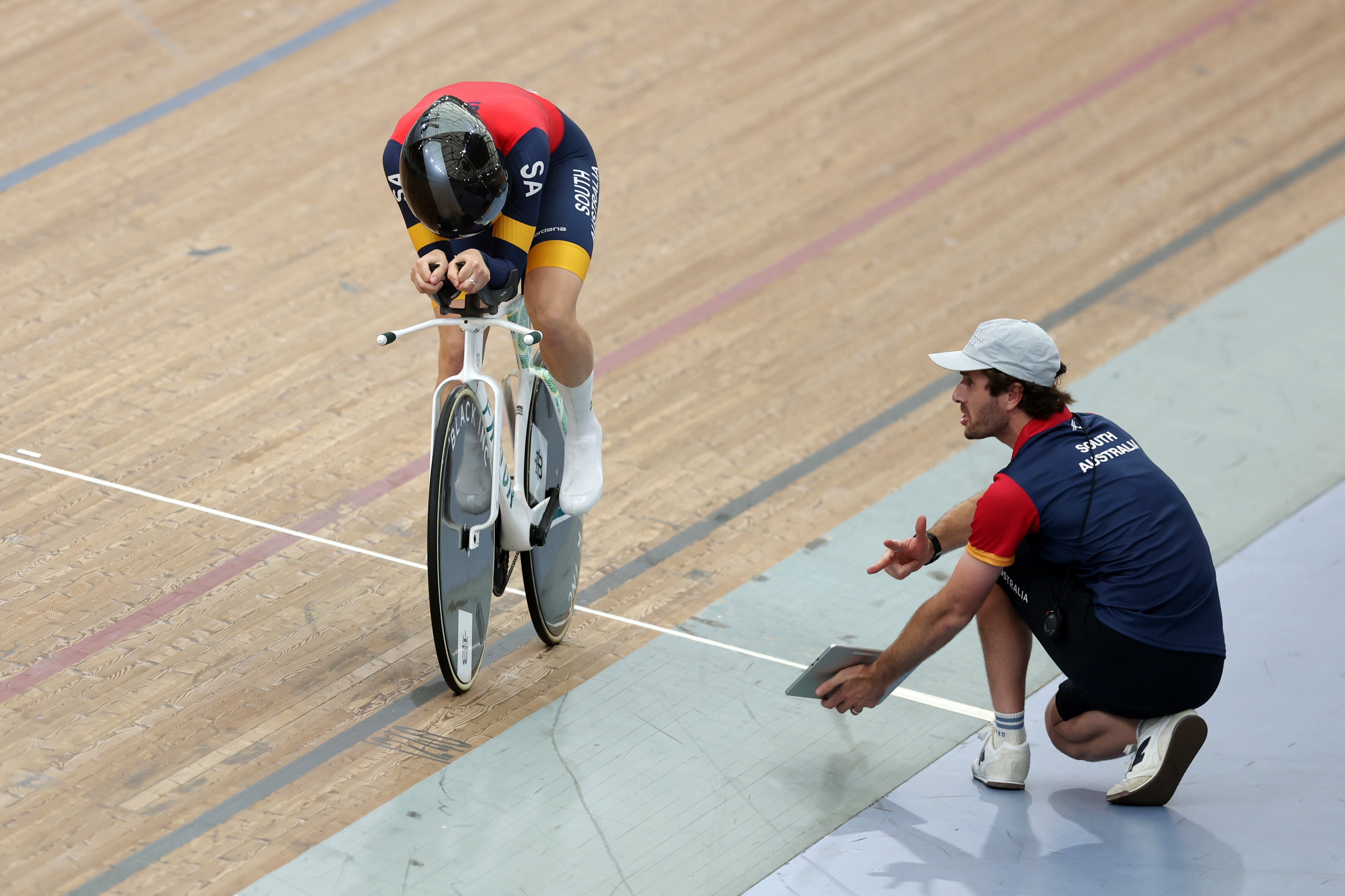 Sophie Edwards rides her bike at a velodrome watched by an official