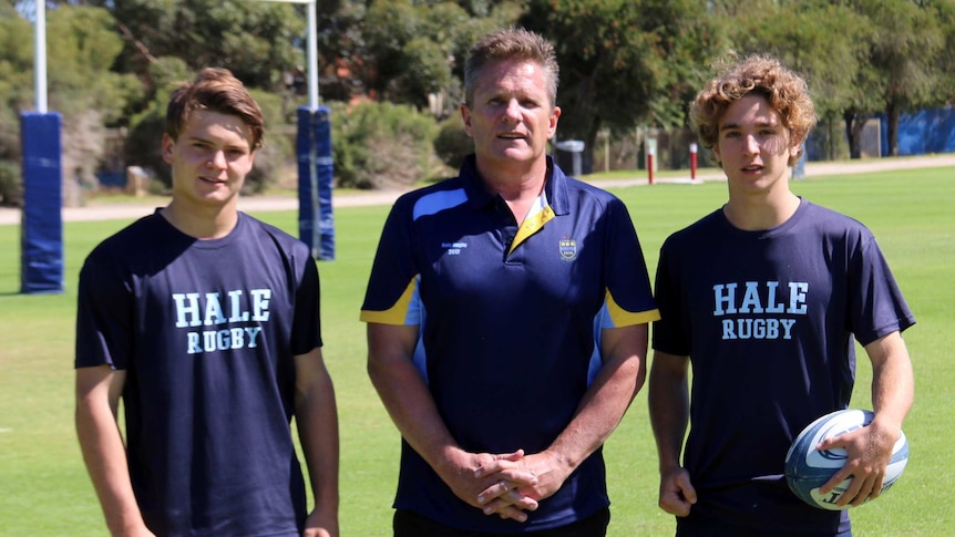 Shaun Tatlow, Steve McFarland, Flynn Peacock - young rugby players and coach stand in a field.