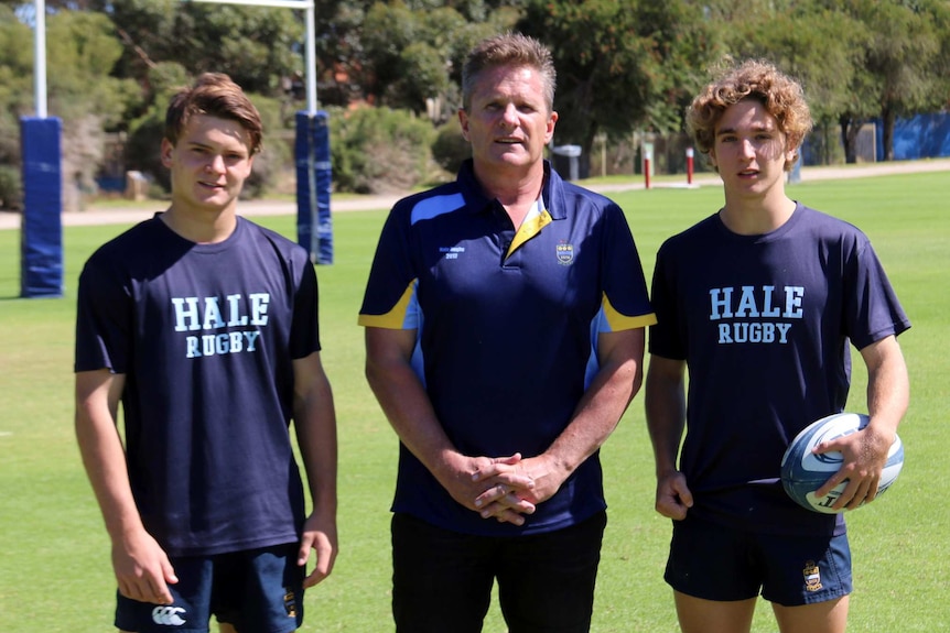Shaun Tatlow, Steve McFarland, Flynn Peacock - young rugby players and coach stand in a field.