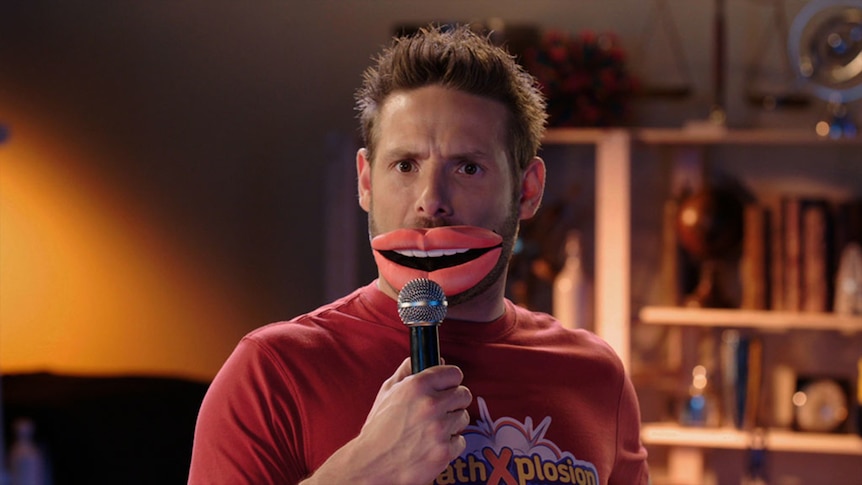 Man wears oversized fake lips, holds microphone up to mouth