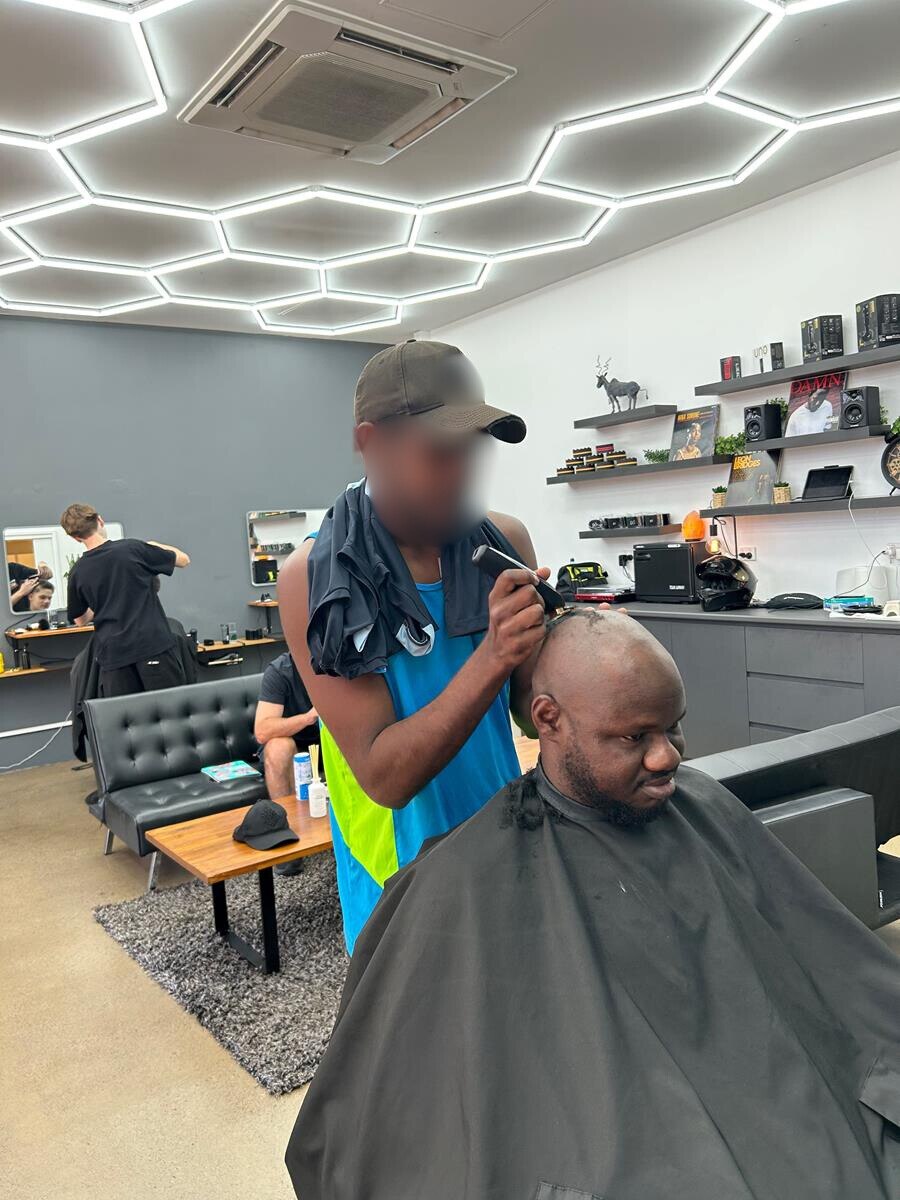 a young man shaving a man's head in a salon