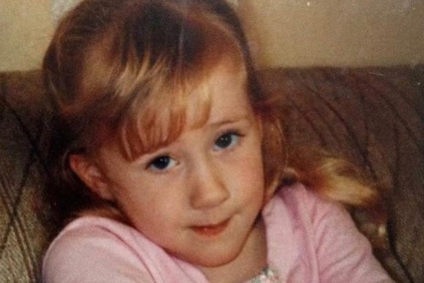 A photograph of a little girl with blonde hair and a fringe