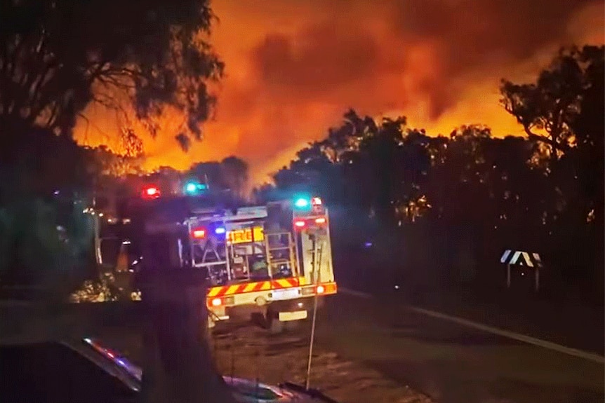 A fire engine in front of an orange-lit night sky