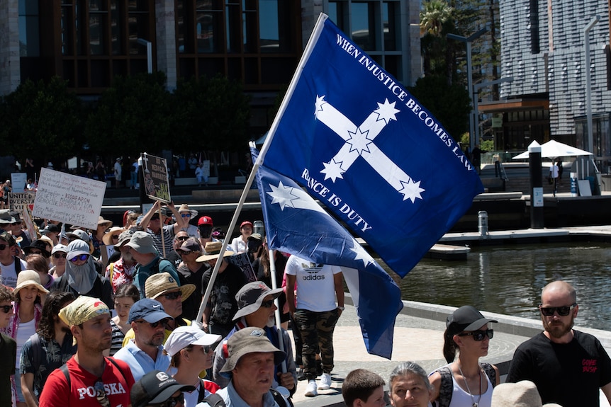 The Eureka flag with the words 'when injustice becomes law' is flown at a rally