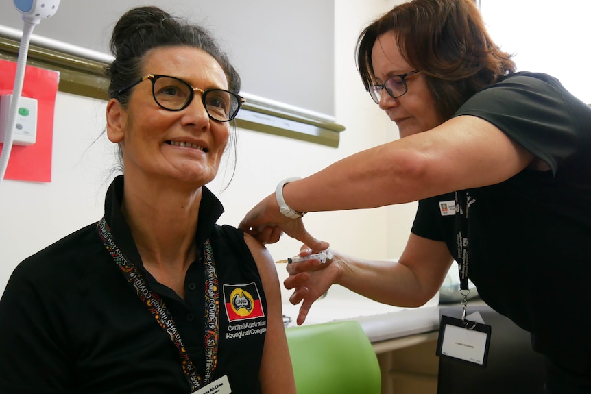 Donna Ah Chee smiles as she receives a COVID-19 vaccine in her left arm.