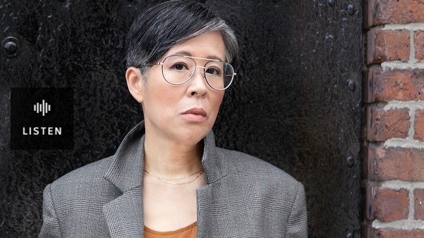 An Asian woman in glasses standing in a brick doorway. Has Audio.
