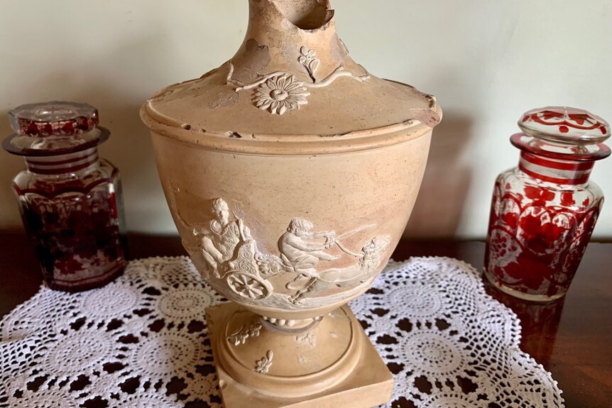 An old piece of pottery with a white embossed chariot drawn by a horse