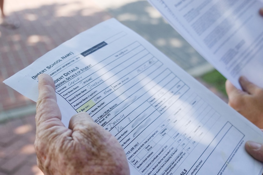 close up of hands holding enrollment paperwork