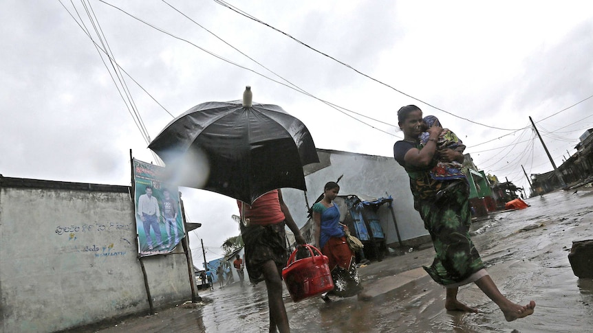 Women carry bags and children after cyclone Phailin hits