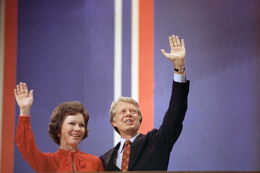 Jimmy Carter and wife Rosalynn smile and wave.