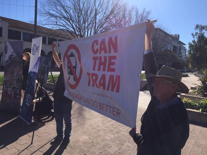 Anti-light rail protestors hold up a banner