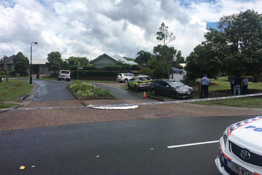A police cordon over the end of suburban street, officers in the foreground