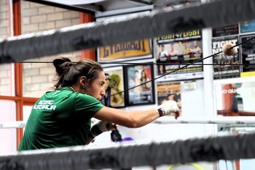 A female boxer, Tiana Echegaray, is shadow boxing in the ring as she trains.