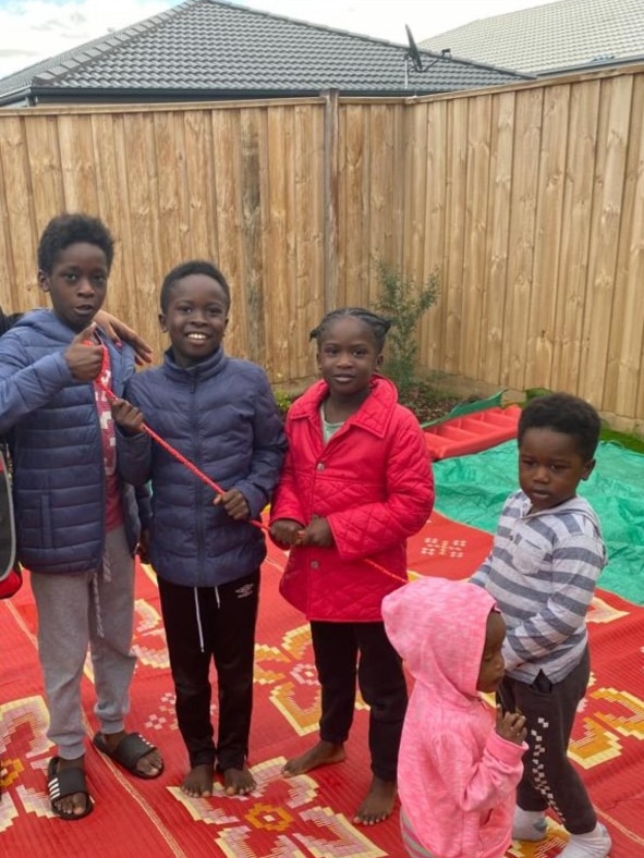 The five young Turgem children gathered in a backyard, smiling, in puffer jackets.