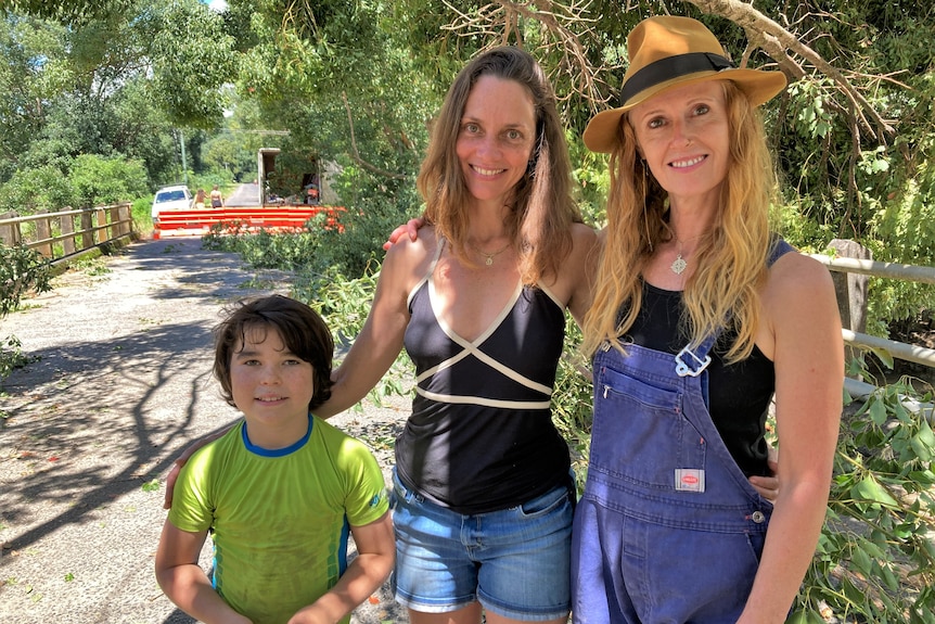 Young boy and two women posing for camera with trees in background