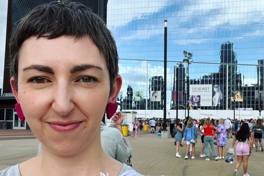 Picture of Dr Hannah McCann, who has short brown hair and is wearing a grey T-shirt, at a Taylor Swift concert.